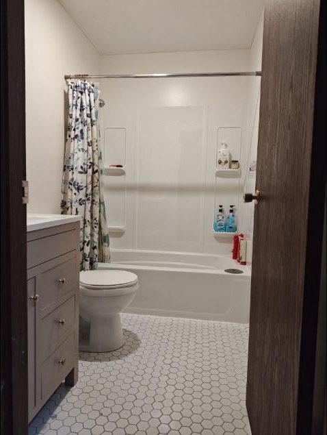 Finished bathroom with a new tub surround, tile floor and updated vanity