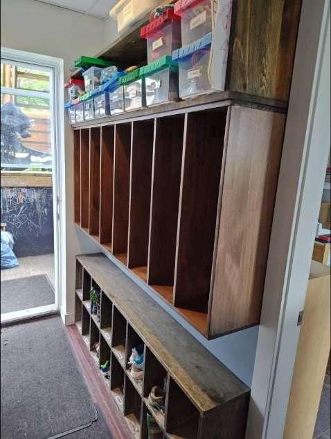 Built-in wooden lockers with a bench and shoe cubbies in an entryway
