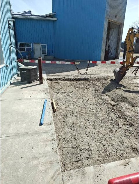 Excavated and graded ground beside a commercial shop building