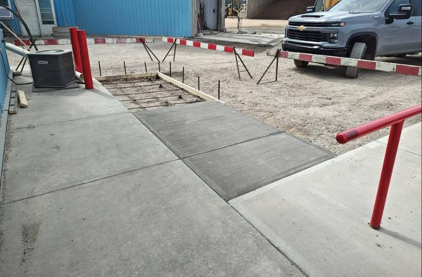 Finished concrete apron and walkway with bollards outside a shop